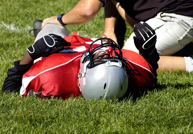 Injured American football player laying on a grass